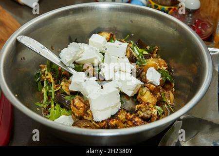 Feta cheese, baked eggplant and arugula in salad bowl. Step by step recipe Stock Photo