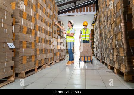 Teamwork of Workers In Warehouse preparing goods cardboard boxes on a pallet in warehouse for dispatch. Stock Photo