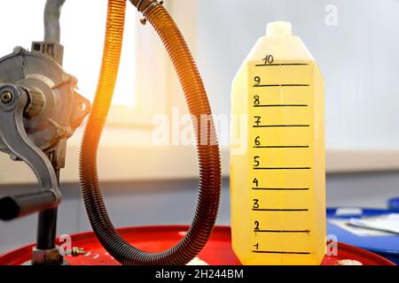 The measuring canister is filled with oil or gasoline and a hand pump for pouring combustible fuel. Gas station. background Stock Photo