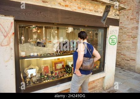 VENICE, ITALY - May 20, 2016: A woman looking at jewelry behind a window of a shop Stock Photo