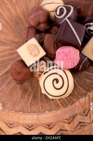 Broken bars of milk chocolate with nuts and sublimated berries and chocolate candies on rustic wooden background, with blank space for text top view, Stock Photo