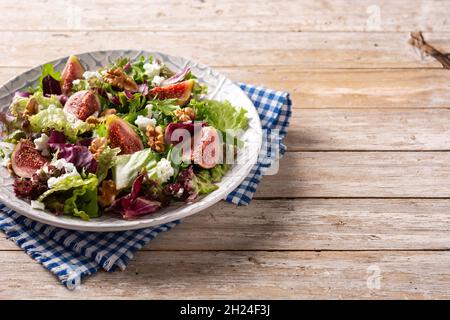 Figs salad with cheese and walnuts on wooden table. Stock Photo
