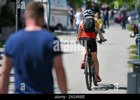 Eine junge Frau auf einem Fahrrad auf der Esplanade in Gmunden bei Sonnenschein, Österreich, Europa - A girl on a bicycle on the Esplanade in Gmunden Stock Photo