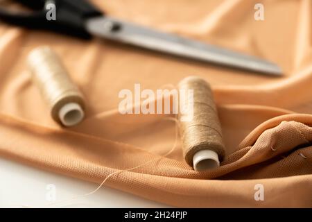 Sewing background with tailor equipment on the peach colored cloth. Selective focus. Stock Photo