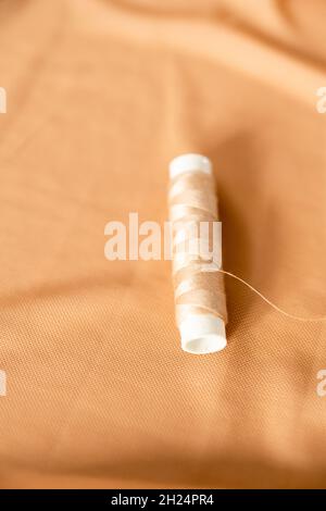 Sewing background with tailor equipment on the peach colored cloth. Selective focus. Stock Photo