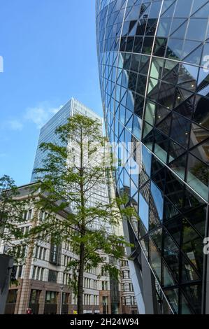 A skyward look up the curved facade of The Gherkin building with the 100 Bishopsgate skyscraper in the background in City of London, England. Stock Photo