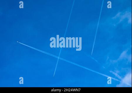 Airplanes at high altitude slicing up the sky above City of London with their contrails. London, England. Stock Photo