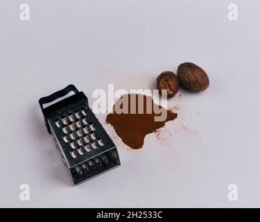 A small grater with nutmeg and powder, isolated on a white background Stock Photo