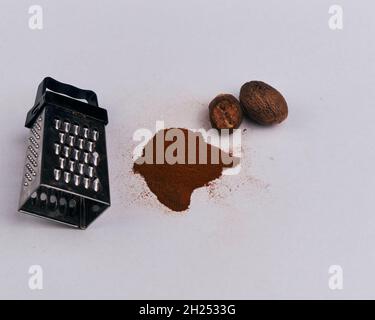 A small grater with nutmeg and powder, isolated on a white background Stock Photo