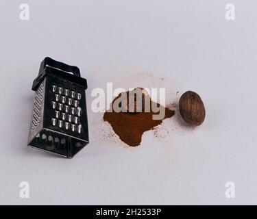 A small grater with nutmeg and powder, isolated on a white background Stock Photo