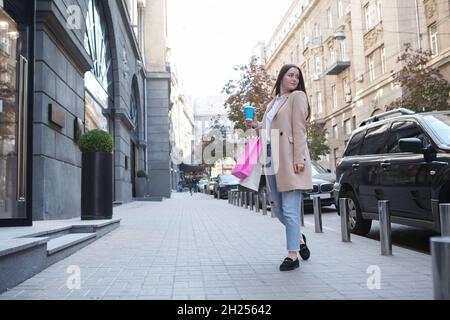 Stylish young woman drinking coffee on the go, walking with shopping bags, copy space Stock Photo
