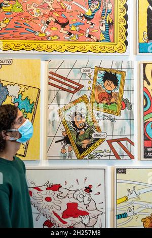 London, UK.  20 October 2021. A visitor views a wall of extracts from classic Beano comics.  Preview of “Beano: The Art of Breaking the Rules”, a new exhibition at Somerset House celebrating the world’s longest-running weekly comic and a British cultural icon: Beano. Curated by artist and lifelong Beano fan Andy Holden, works by writers, musicians, painters, sculptors and photographers are displayed alongside original comic artwork and artefacts from the Beano’s archive in an exhibition which runs 21 Oct 2021 to 6 Mar 2022.  Credit: Stephen Chung / Alamy Live News Stock Photo