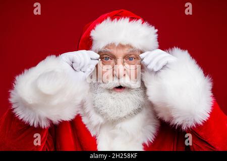 Photo of funky impressed man pensioner dressed santa claus costume arms glasses big eyes isolated red color background Stock Photo