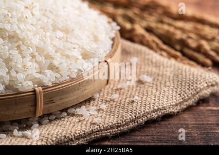 Raw white polished milled edible rice on wooden table background in a bowl, organic design concept. Stock Photo