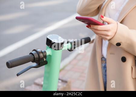 Unrecognizable woman using mobile app on her smart phone to rent electric scooter Stock Photo