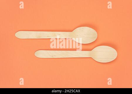 Eco-friendly disposable tableware made of bamboo. Two wooden disposable spoons on orange background, close up Stock Photo