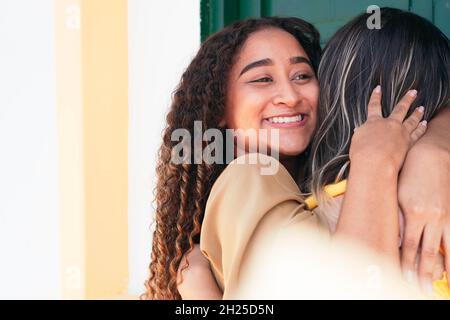 Happy meeting of two friends hugging on the street. Smiling friends laughing and hugging in the center of the city. Stock Photo