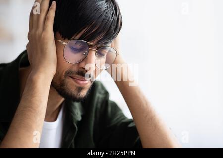 Indian guy touching his head, suffering from migraine Stock Photo