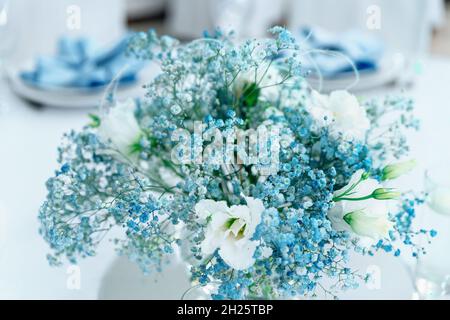 Wedding decor with beautiful flowers. Close up of blue gypsophila and white eustoma in a bouquet. Beautiful festive table decorated with bouquet of fl Stock Photo