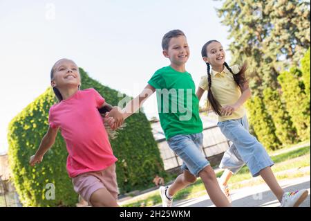 Boy and two girls running in park Stock Photo