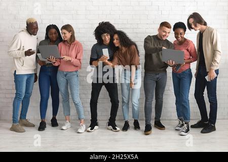 Cheerful multiracial millennials using gadgets while spending time together Stock Photo