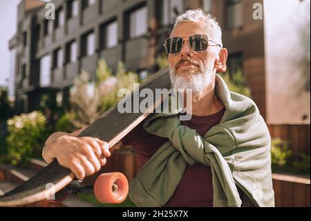 Serious skateboarder in sunglasses staring into the distance Stock Photo