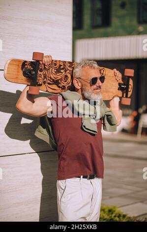Skateboarder in sunglasses standing by the wall outside Stock Photo