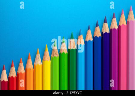 Colour pencils arranged diagonally on a blue paper background. Stock Photo