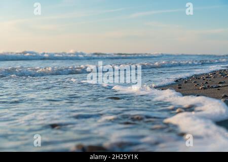 Close-up of foaming sea waves rolling onto a sandy beach on the beach. Stock Photo
