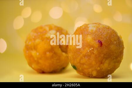 ball shaped sweets known as laddu or laddoo, popular sugary food in indian festivals, closeup view in decorated background Stock Photo