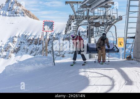 Glacier 3000, Les Diablerets, Switzerland - October 31, 2020: Two people on skis coming down from the chairlift Stock Photo
