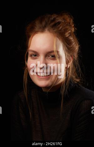 serious sad young woman with down syndrome on black background looking at camera smiling Stock Photo