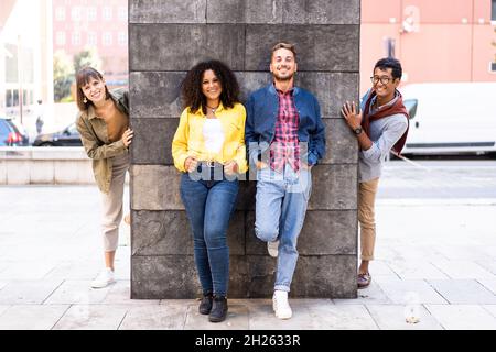 Multiracial friends group having fun at wall on university college campus - Diverse culture students celebrating outside at the city - Young smiling p Stock Photo