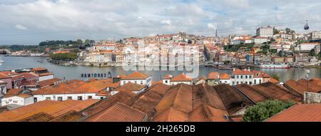 Porto Portugal, Panoramic view with rooftops of Port wine cellars in front, Ribeira district of Porto behind at River Douro, Portugal. Stock Photo