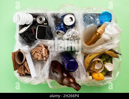 Top view photo of segregated waste materials laid on green isolated background. waste management concept Stock Photo