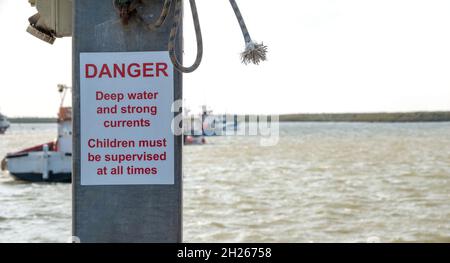 Danger warning sign of strong currents on the quay at Orford Ness Suffolk Stock Photo