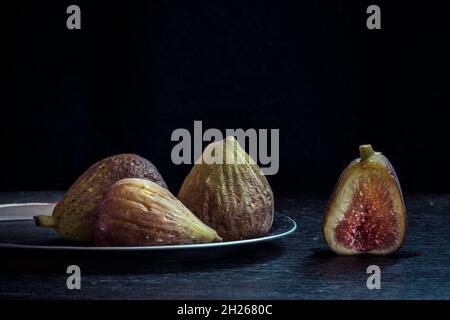 Figs on a metal plate lying on an old wooden background Stock Photo