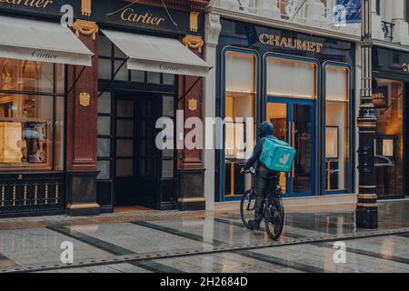 London, UK - October 02, 2021: Deliveroo driver in front of Cartier store on Bond Street, one of the most famous streets for luxury shopping in London Stock Photo