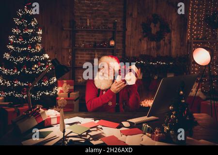 Photo portrait santa with white beard wearing glasses trying to guess whats in box Stock Photo