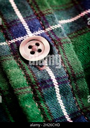 Closeup of button on green plaid flannel shirt worn for fashion and warmth in Fall or Winter Stock Photo
