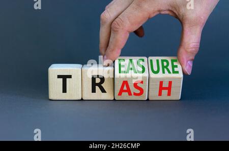 Trash to treasure symbol. Businessman turns cubes and changes the word trash to treasure. Beautiful grey table, grey background. Business, trash to tr Stock Photo