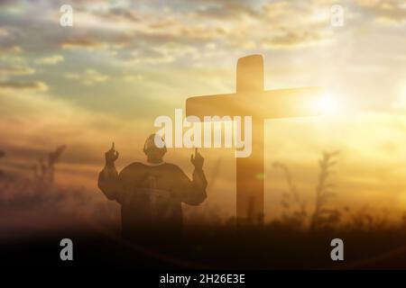 Silhouette of man raising hands worship and praise God. Christian Religion concept. Stock Photo