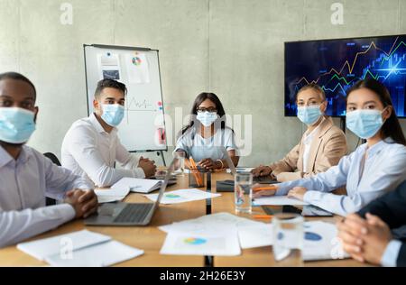 Safety At Work. Business People In Masks Having Corporate Meeting In Office Stock Photo