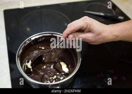 Step-by-step process for making a sour cream chocolate cake. The process of making chocolate glaze. Butter is added to the heated mixture of sour crea Stock Photo