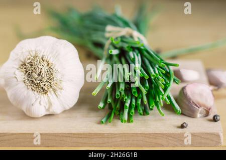 A bunch of green onions, garlic, pepper on a wooden board Stock Photo