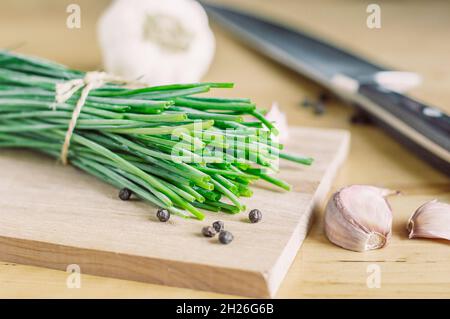 A bunch of green onions, garlic, pepper on a wooden board Stock Photo