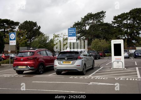 Nissan Leaf and MG EV charging at Pod Point electric vehicle charging point sponsored by VW  Tesco Churchdown UK Stock Photo