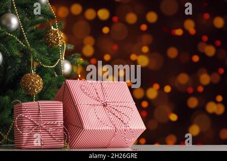 New Years gift boxes under the Christmas tree on a blurred background of lights. Stock Photo