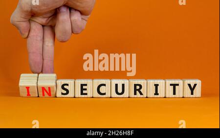 Security or insecurity symbol. Businessman turns wooden cubes, changes words insecurity to security. Beautiful orange background. Business, security o Stock Photo