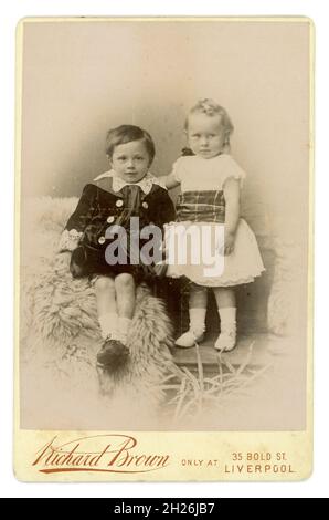 Victorian cabinet card of 2 children, brother and sister, the boy wears a Little Lord Fauntleroy style velvet jacket with lace collar. From the studio of Richard Brown, Liverpool, England, U.K. circa 1895 Stock Photo